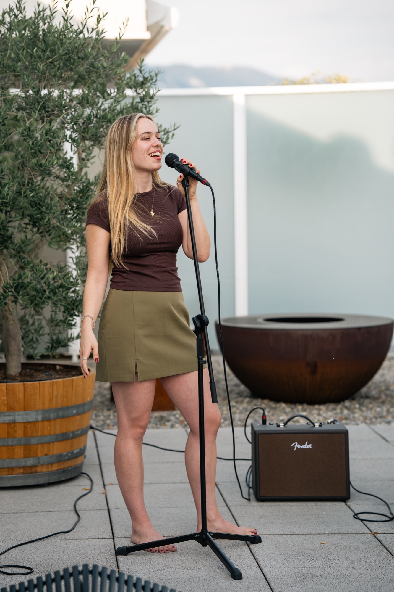 Helena singing and smiling on a rooftop terrace